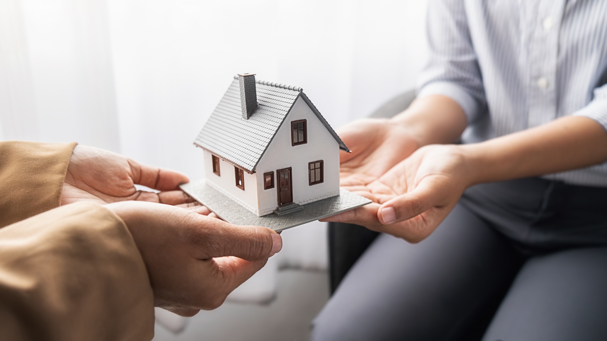Hands holding a small home representing estate planning